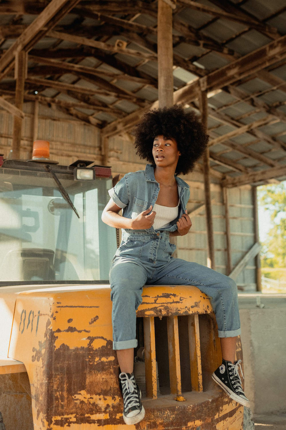 Woman posing for a photo wearing denim overalls and a white top underneath